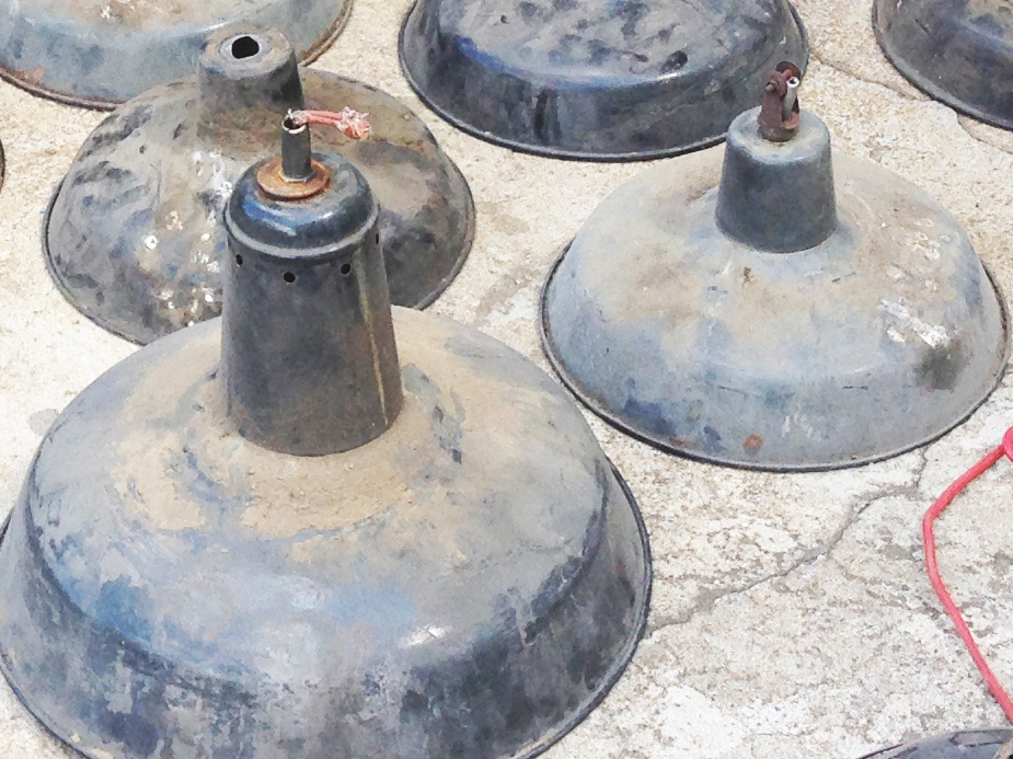 Alte, verstaubte Industrielampen im Fundzustand Mehrere alte Emaillelampen stehen auf einem Betonboden. Die Lampenschirme sind schwarz aber sehr schmutzig und verstaubt